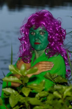 Alacakaranlıkta yeşil ortasında bir su cadı şeklinde bir kadın yüzü.