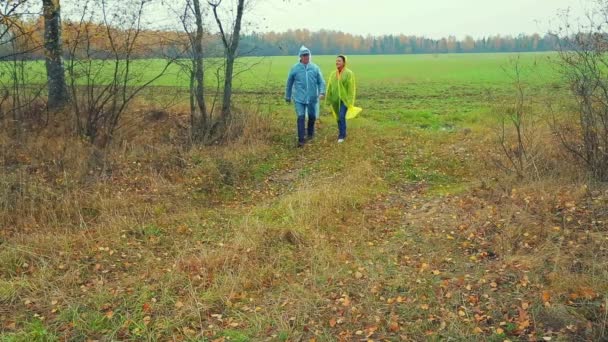 Seorang pria dan seorang wanita agronomis dalam mantel hujan kembali dari lapangan — Stok Video
