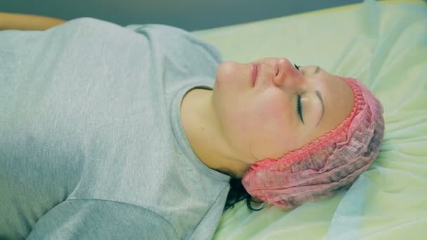 La tête d'une femme coiffée d'un bonnet cosmétique couchée sur le canapé. Gros plan . — Video