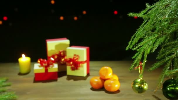 Weihnachtsbaum mit Kugeln neben den Geschenken auf dunklem Hintergrund mit Lichtern. — Stockvideo