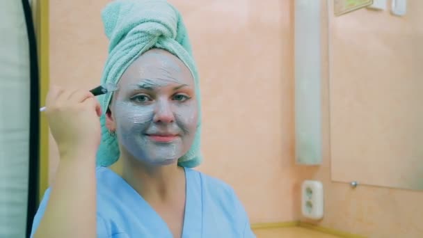 一个面带微笑的女人的脸 头上戴着毛巾 皮肤上有一抹蓝色的黏土 平均计划 — 图库视频影像