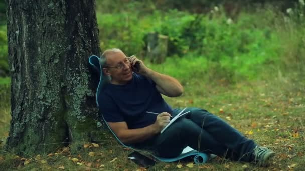 Homme Souriant Lunettes Est Assis Sous Arbre Dans Parc Écrit — Video