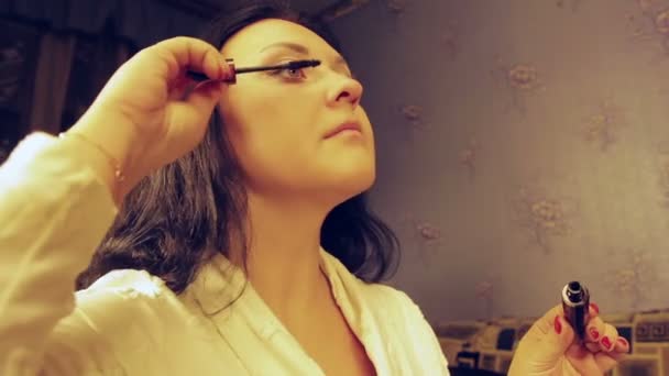 Eine junge Frau bemalt Wimpern mit Wimperntusche. der durchschnittliche Plan. — Stockvideo