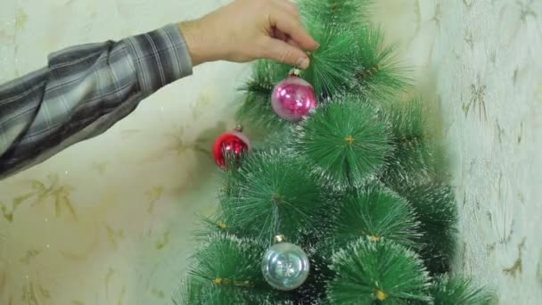 Mannelijke handen opknoping feestelijke ballen in de kerstboom. — Stockvideo