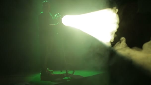 Un illuminateur mâle dirige un faisceau de lumière à partir d'un projecteur de profil et travaille avec un profil . — Video