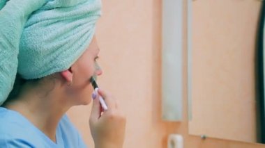 Genç bir kadın çamur maskesi yüzünde bir fırça ile uygulanır. Yakın çekim. Yan görünüm.