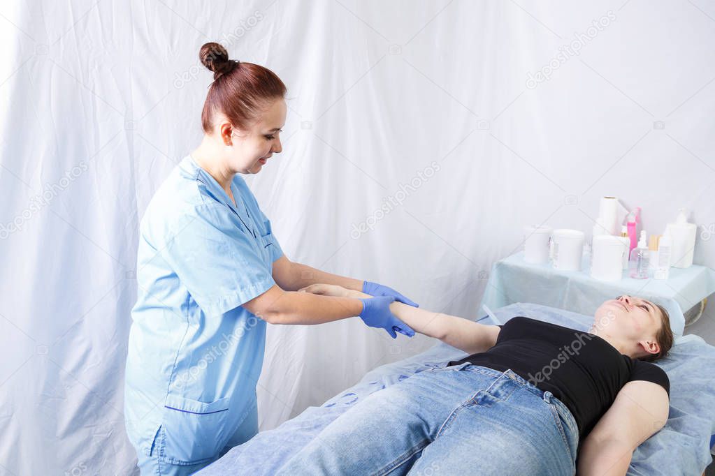 Smiling woman doctor doing a womans massage of the womans right hand