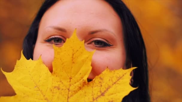 Una foglia d'acero davanti a una giovane donna in un parco autunnale . — Video Stock