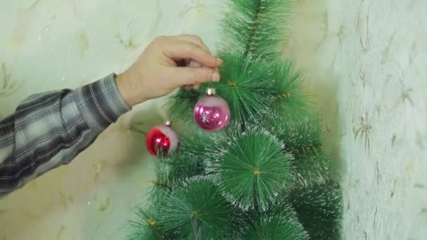 Mens handen Versier de kerstboom met feestelijke ballen — Stockvideo