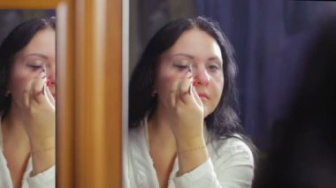 Beyaz önlük bir ayna önünde genç bir kadın gözleri gölgeler bir fırça ile boya.