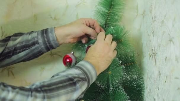 Mens handen Versier de kerstboom met feestelijke ballen — Stockvideo