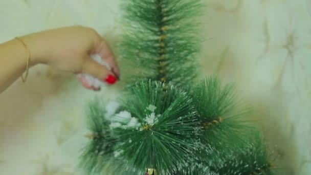 Mão feminina. A mão decora uma árvore de Natal pela imitação da neve — Vídeo de Stock