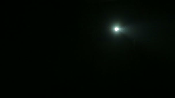 Луч света от прожектора, направленного на сцену в полной темноте — стоковое видео