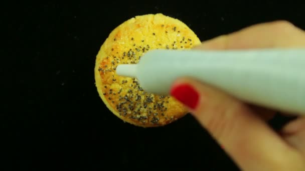 Una mano femminile tiene un tubo di marmellata gialla culinaria e disegna divertenti emoticon sui biscotti. Giri temporali — Video Stock