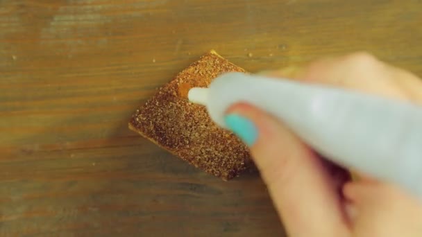 Een hand houdt een buis van het koken van verf en grappige gezichten is geïnspireerd op de chocoladeschilferkoekjes met gele verf — Stockvideo