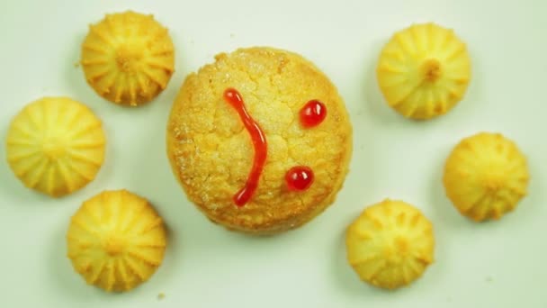 Biscoitos de manteiga com tinta culinária pintados com um emoticon engraçado e cercados por pequenos biscoitos. Movimento em círculo — Vídeo de Stock