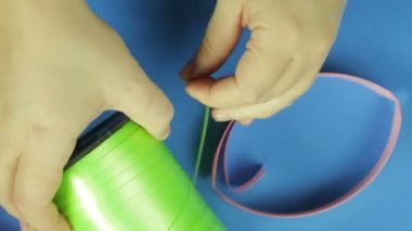 Eller yeşil bobin teypten makasla kesme. Mavi arka plan. El yapımı