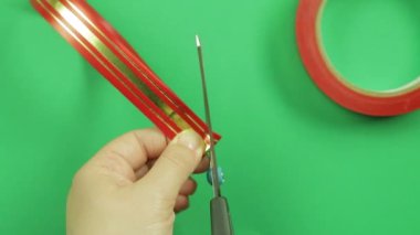 Kadın el bir kırmızı kurdele hediye yay yaprakları düzeltmek ve şekil vermek. Yeşil arka plan