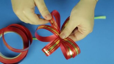 Kadın el Kırmızı kurdele fiyonk şekli verin. Mavi arka plan