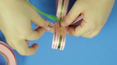 Kadın el bir pembe kurdele hediye yay yaprakları şekil. Mavi arka plan