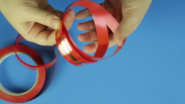 Het maken van een geschenk buigen in het rood op een blauwe achtergrond. Tijd ronden — Stockvideo