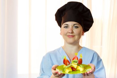 Kivi, çilek ve şeftali bir aşçı kadın elinde yapılmış canaps bir tabak. yatay fotoğraf.
