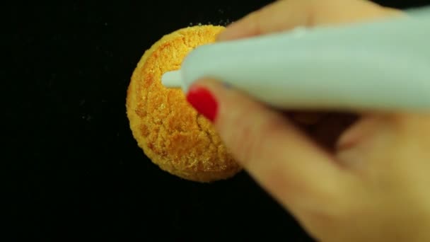 Una mano femenina sostiene un tubo de leche condensada y dibuja divertidos emoticonos en las galletas. Vueltas de tiempo — Vídeos de Stock