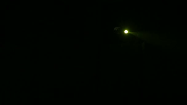 Un haz de luz amarilla de un proyector de perfil dirigido al escenario en completa oscuridad — Vídeos de Stock