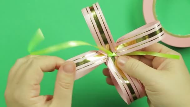 Female hands straighten the petals of the bow blank on a green background. — Stock Video