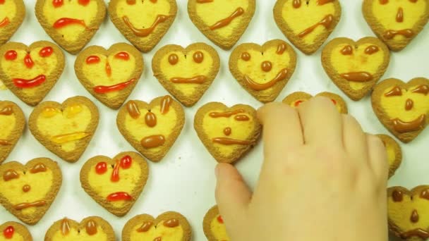 A woman is laying a cookie with a pattern of painted emoticons with icing on a white dish — Stock Video