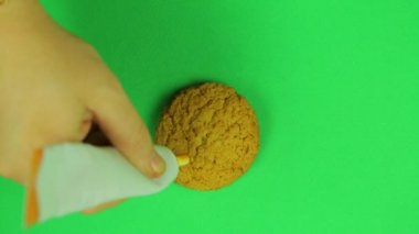 Çocuk üzerinde bisküvi dolar işareti buzlanma kahverengi yeşil bir arka plan üzerinde çizer. Zaman sukut. El yapımı