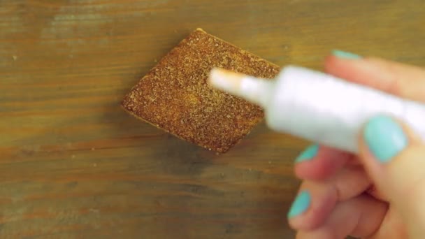 Een hand houdt een buis van het koken van verf en trekt harten op een chocolade cookie met rode verf. Hand gemaakt. — Stockvideo