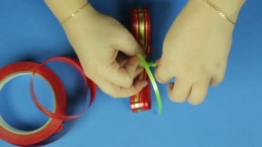 Kadınların elleri boş bir kırmızı kurdele yay yay ile yeşil örgü için bağlamak. Mavi arka plan.