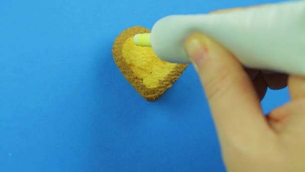 Female Hand Paints Heart Shaped Cookies Blue Background Yellow Icing — Stock Video