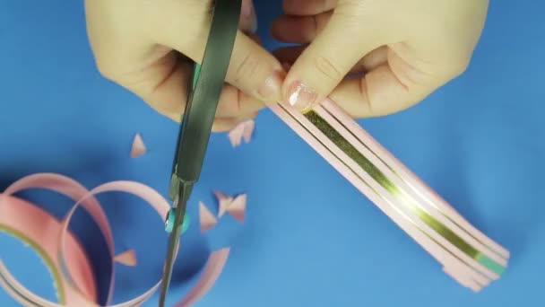 Les mains des femmes coupent les coins d'un blanc rose pour un arc cadeau. Fond bleu — Video