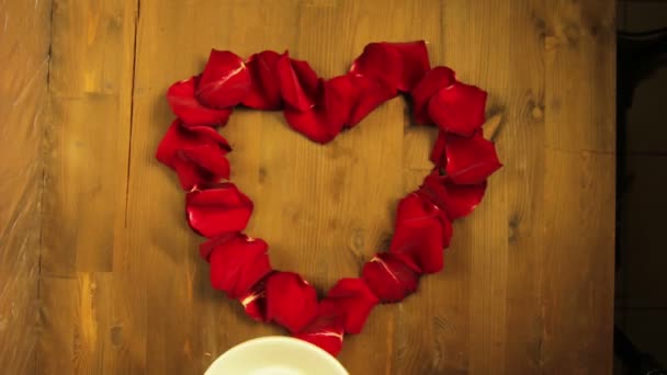 La fille met au milieu du cœur des pétales de rose une tasse de café — Video