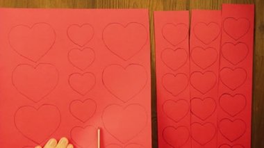 Kız boşlukları kırmızı karton dan kalplerin keser. Yakın çekim