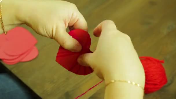 A menina faz um suverner de um coração vermelho de cartão e fio. Desfasamentos temporais — Vídeo de Stock