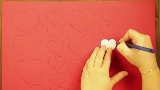 Дівчина малює на червоних картонних серцях. Крупним планом — стокове відео