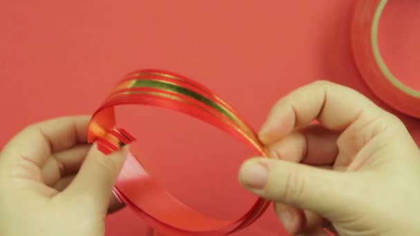 여자 손이 선물 활에 대 한 핑크 보호물이 핑크 끈으로 묶여 있습니다. 빨간 배경 — 비디오