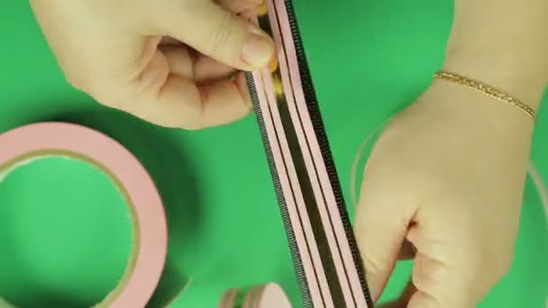 Het maken van geschenk boog roze kleur op een groene achtergrond. Tijd ronden. — Stockvideo