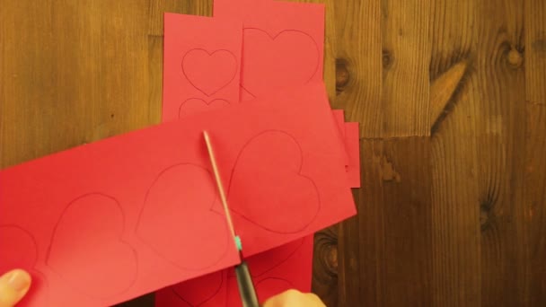 La fille coupe des blancs de cœur de carton rouge .