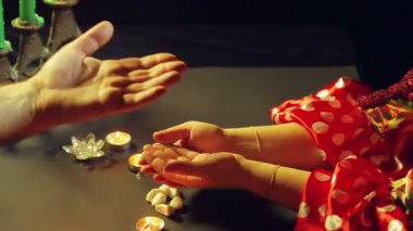 Bir servet salon mum ışığında bir çingene kadın bir adam el tarafından merak ediyor.