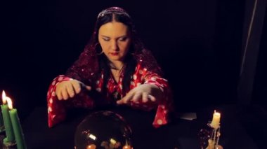 Bir çingene falcı bir mum ışığında masada üzerinde sihirli bir kristal merak ediyor. Ortalama planı