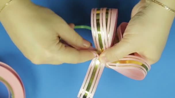 여자 손에 핑크 리본 선물 활의 꽃잎 모양. 파란색 배경 — 비디오