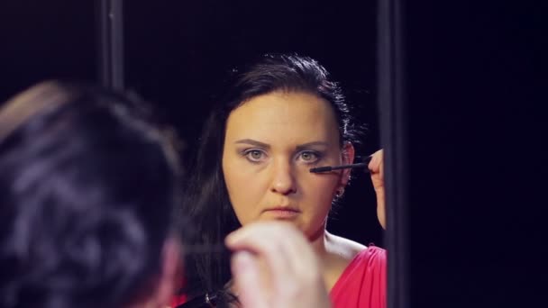 一个穿着红色衣服的年轻黑发女人在镜子前戴上睫毛膏 — 图库视频影像