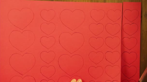 Flickan skär från röd kartong Tom med hjärtan. Tid varv — Stockvideo