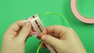 Pembe kurdele boş yeşil bir arka plan üzerinde bir hediye yay için yeşil bir şerit ile kadın elim kolum bağlı.