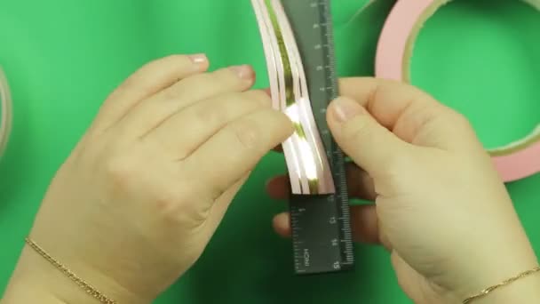 緑の背景のピンクのリボンのパターンを包む女性の手 — ストック動画