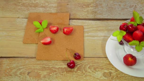 在一个白色的盘子 躺在一个轻木桌子是草莓和樱桃 — 图库视频影像